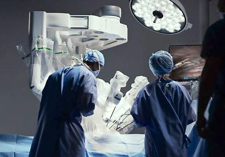 在明亮的手术室里，人们穿着外科手术服从后面拍摄